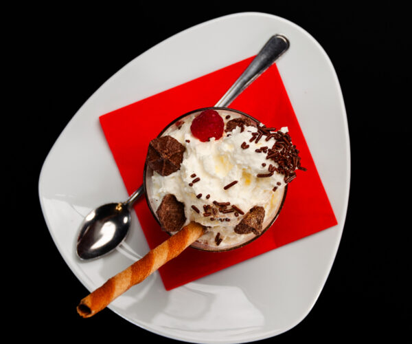 Knusperflocke, eine Kugel Schokoeis mit Knusperflocken, Karamellsoße und Sahne